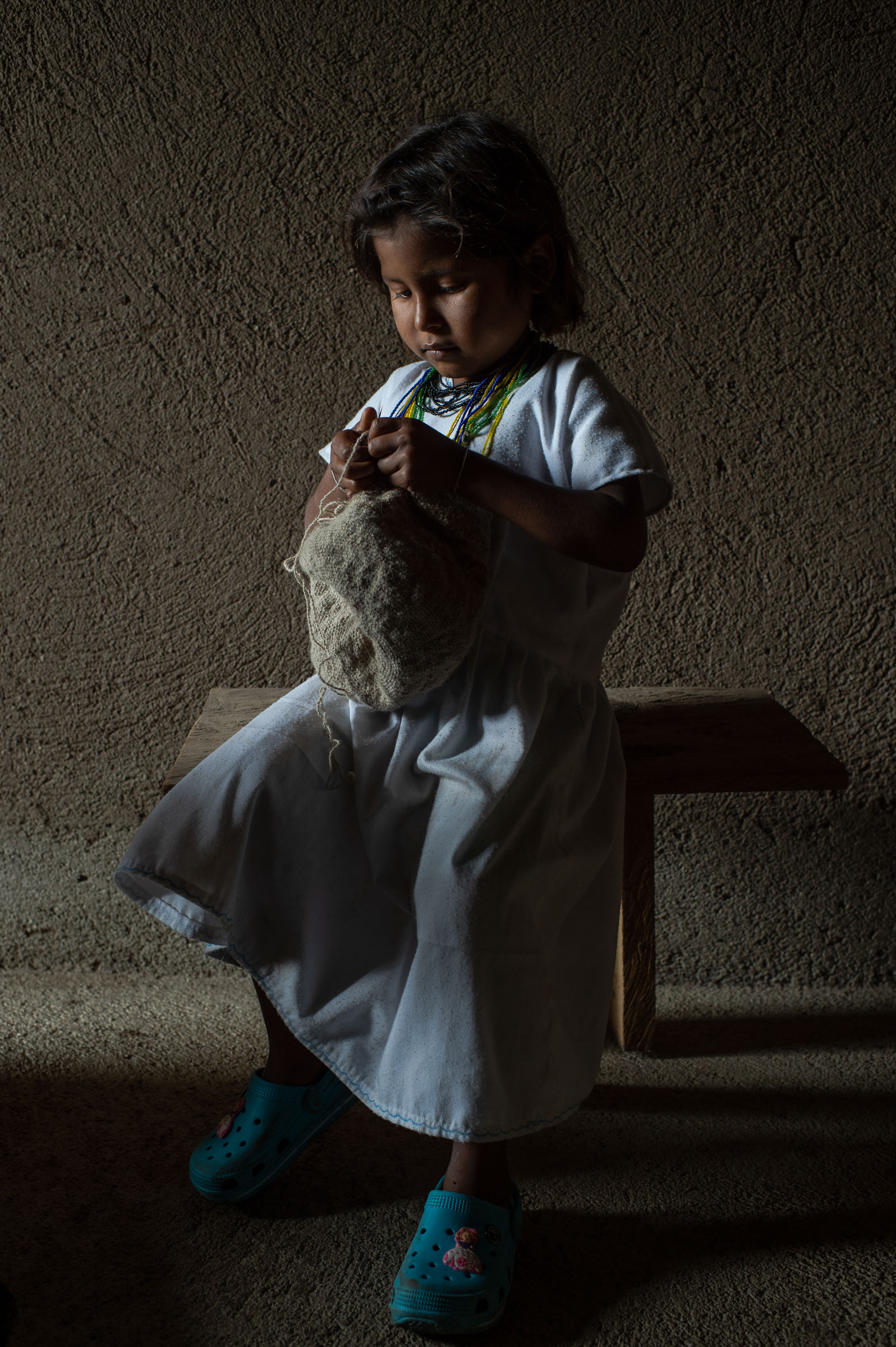 Niña tejiendo una mochila a media luz — Tigre de Salón